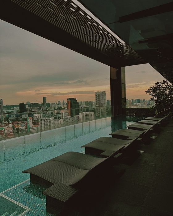 The rooftop pool at dusk, the city beyond