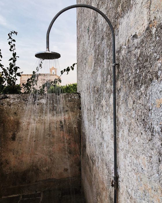 The outdoor shower running against stone