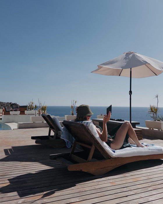 Reading under an umbrella above the sea